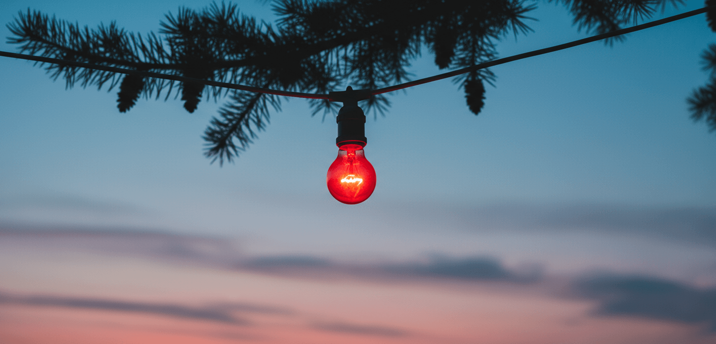 Red light bulb against twilight sky.
