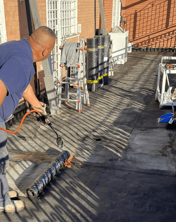 Operatore di kikoristrutturazioni con cannello per gas brucia guaina impermeabilizzante per terrazzi con attenzione