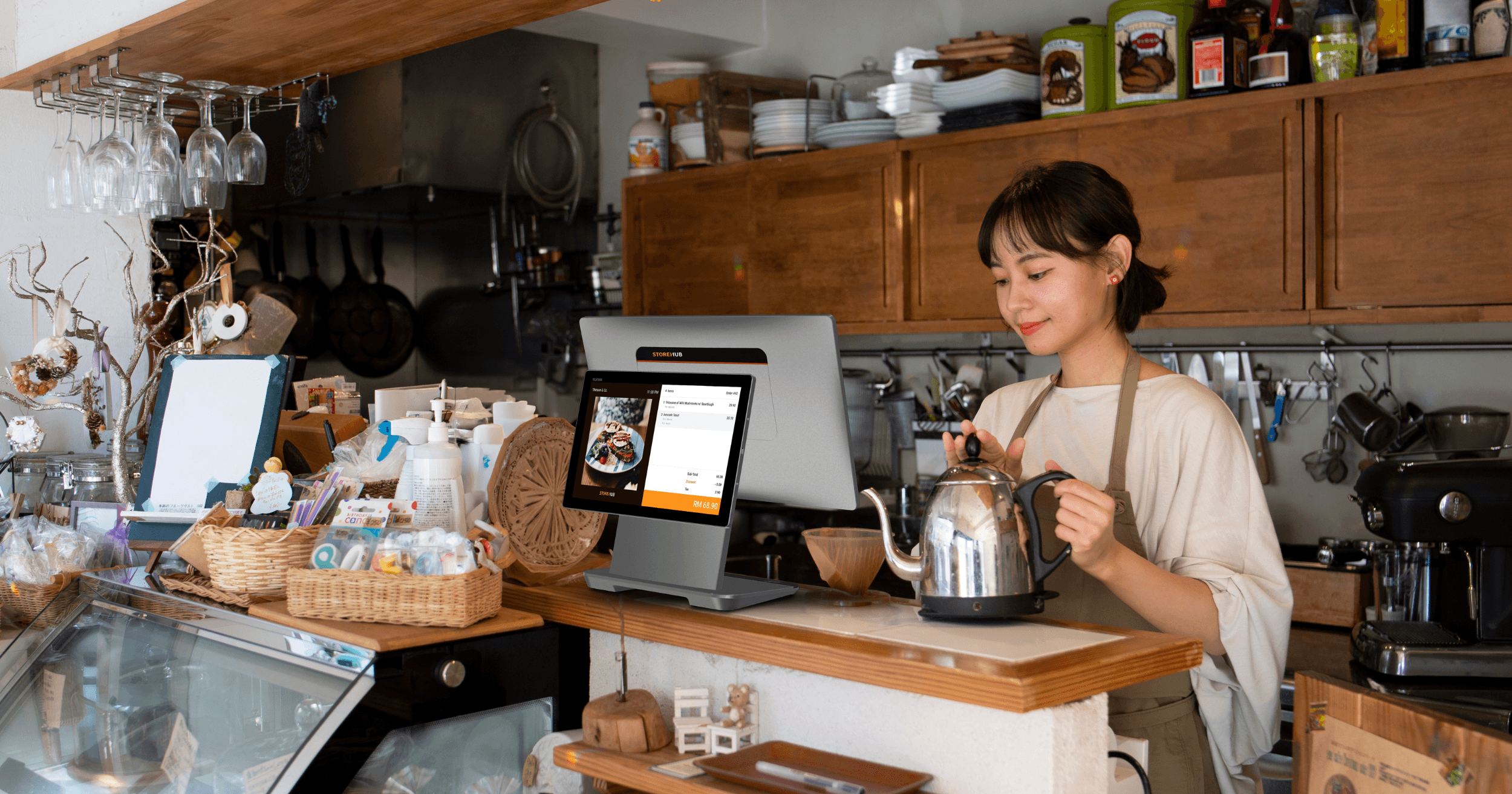 StoreHub POS di atas kaunter dengan pasta dan jus di sebuah kafe.