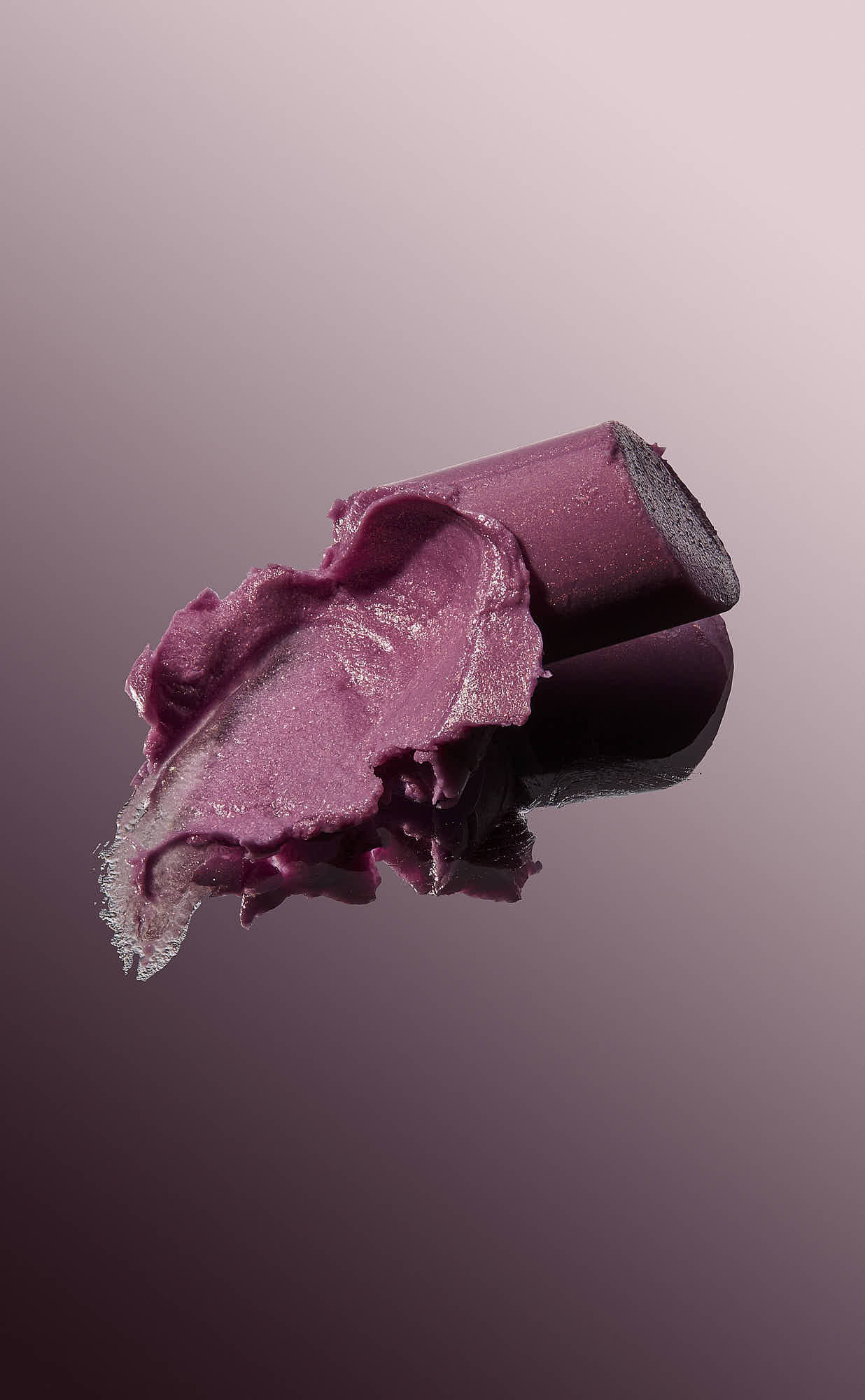 A small, brightly colored object resembling a stylized animal figure, set against a soft, gradient pink background.