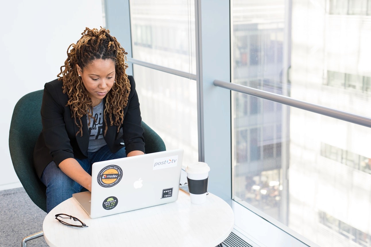 Black woman working on a laptop in a bright sunlit office