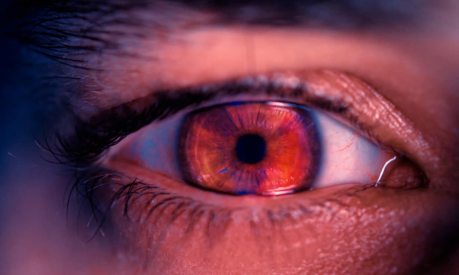 Close-up of a human eye featuring a striking, vivid red iris, surrounded by a subtle blue hue, with the words "Break the Hex" displayed beneath in a bold, modern font.