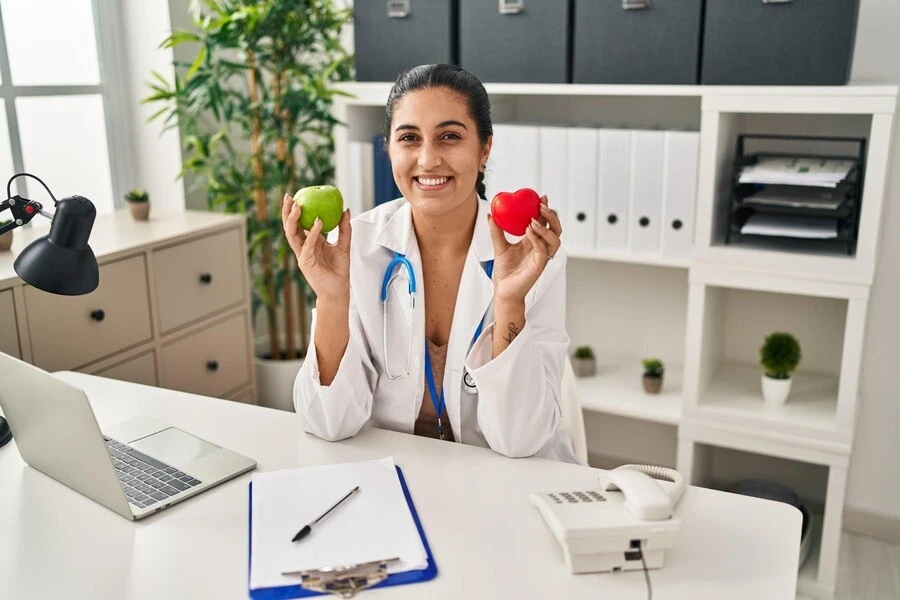 woman-working-dietitian-clinic-holding-green-apple-smiling-with-happy-cool-smile-face-showing-teethwoman-working-dietitian-clinic-holding-green-apple-smiling-with-happy-cool-smile-face-showing-teeth