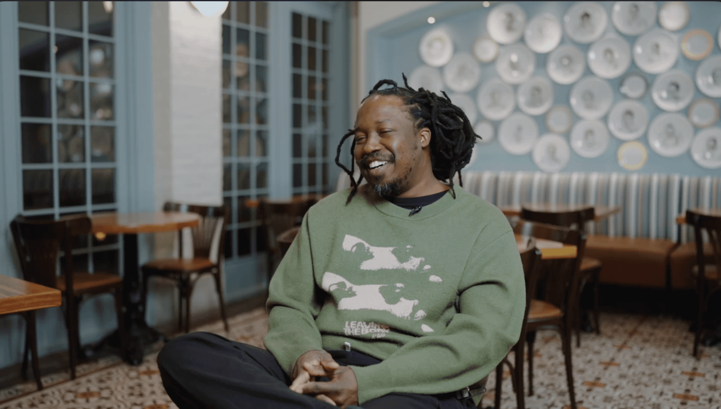 Chef Paul Carmichael sitting in a cafe at the Cullinary Institue of America laughing while he is doing a video interview sitting down