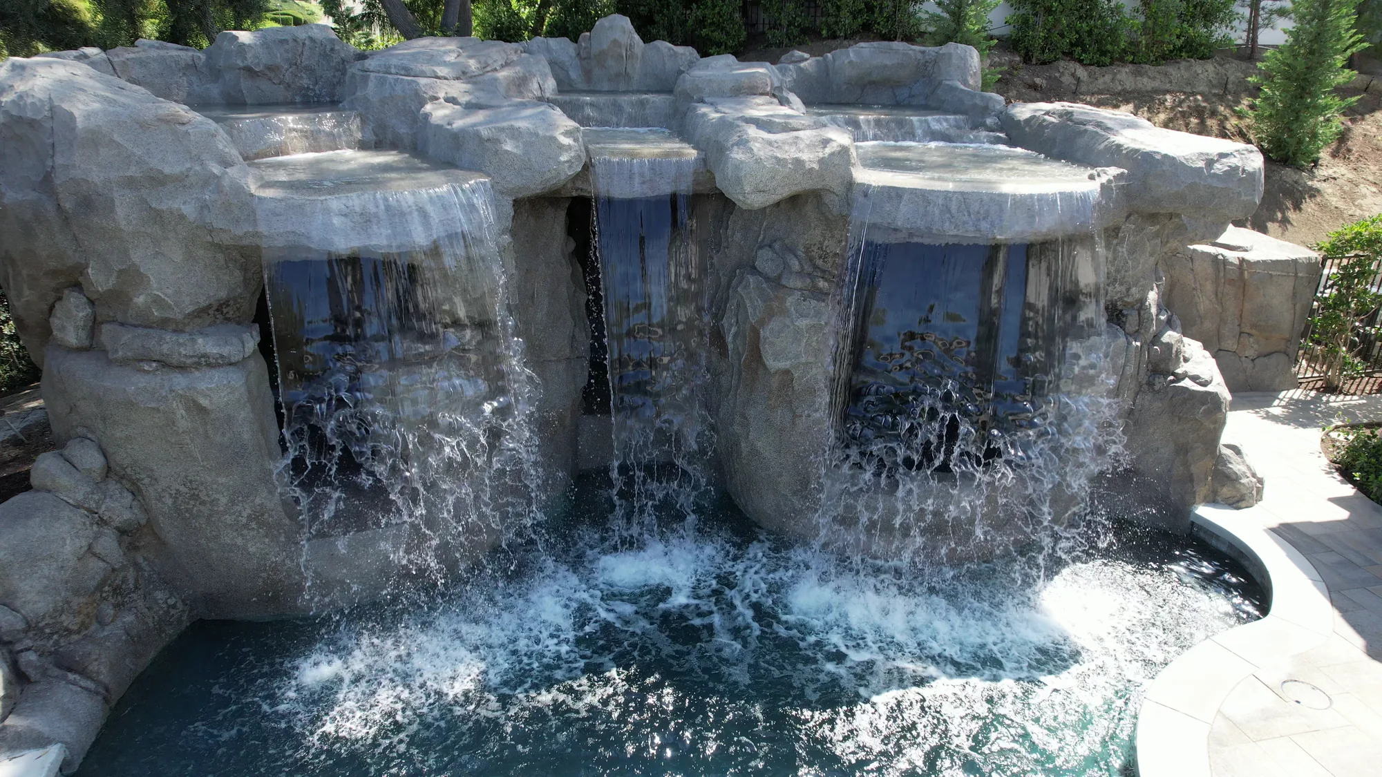 Water cascades from a broad rock grotto into the curved swimming pool.