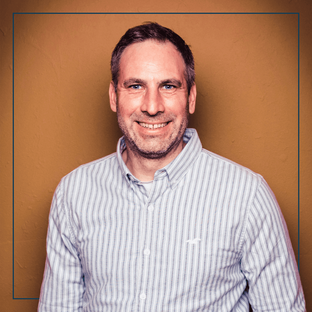 Ein Mann in gestreiften Hemd vor einer orangen Wand