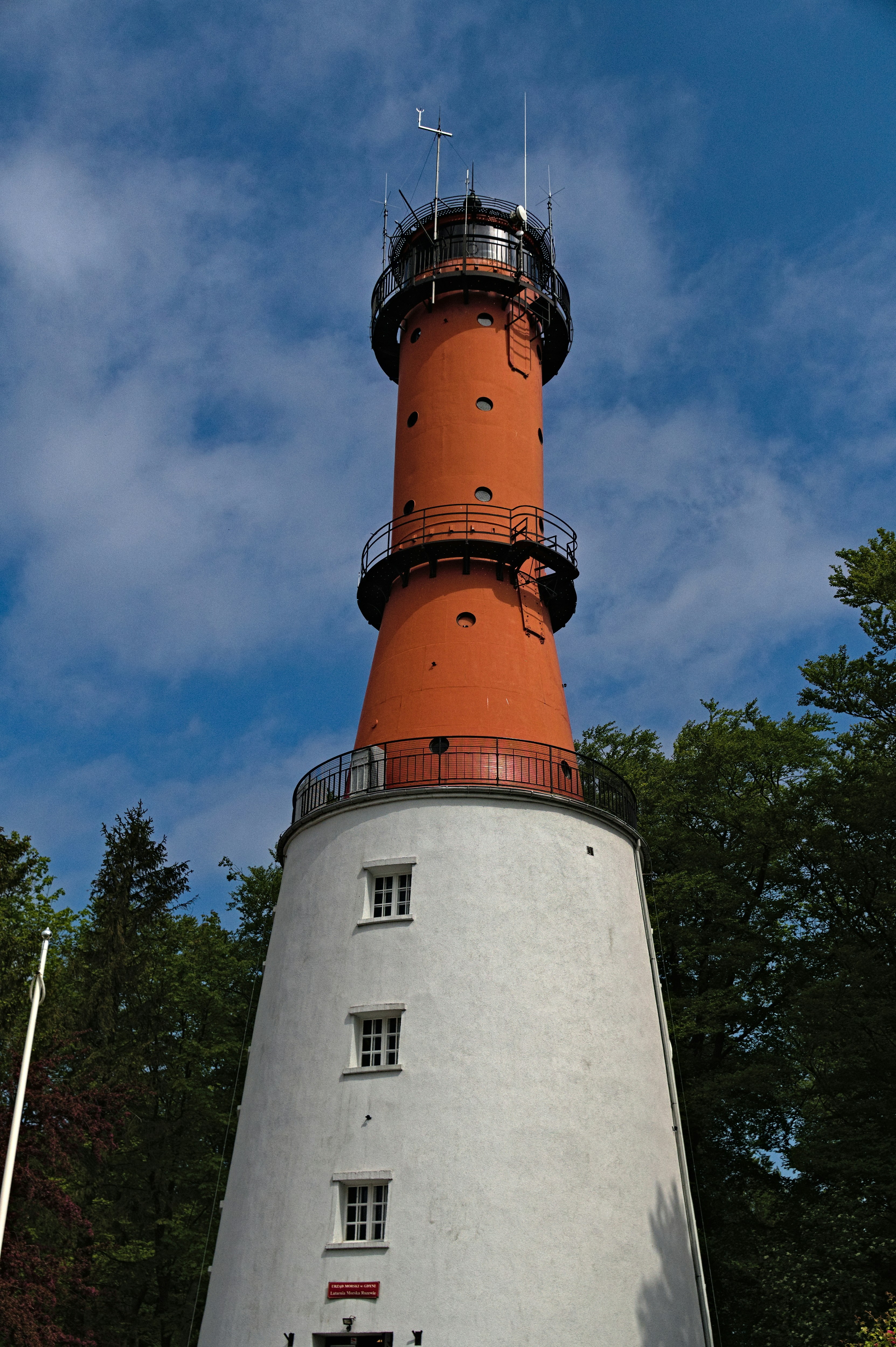 Tall red and white lighthouse against a blue sky.