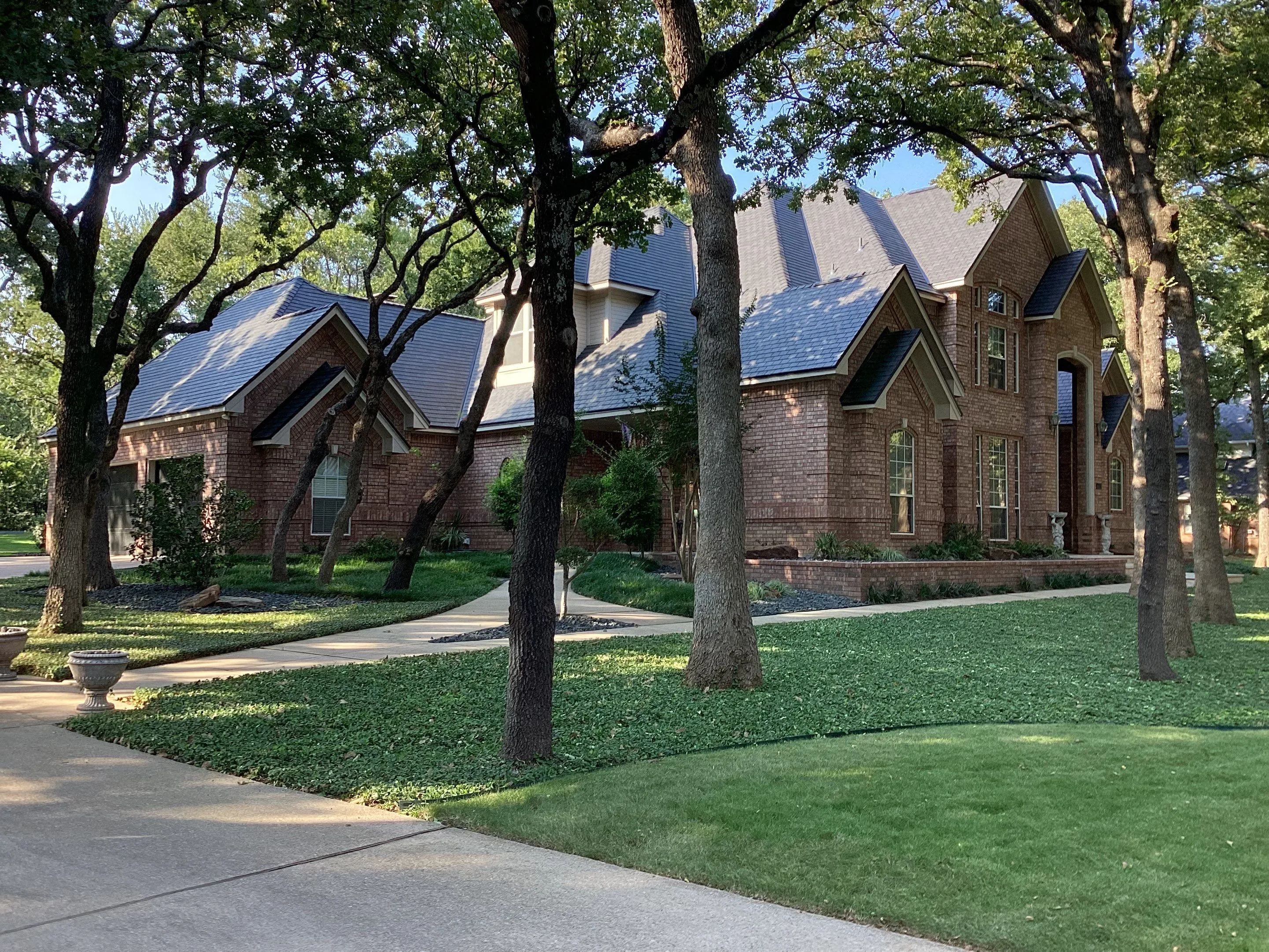 Street view of completed F-Wave synthetic roofing project on brick home in established Corinth Texas neighborhood