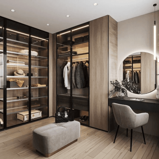 A modern walk-in closet featuring wooden shelving, glass doors, a mirror, and a cushioned ottoman.