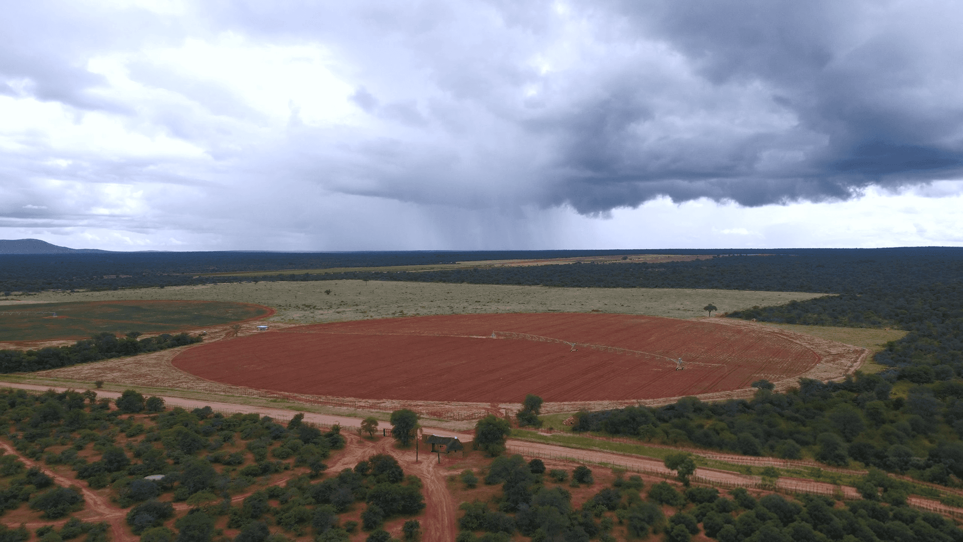 Modern two-story house with glass railings and stone facade, surrounded by desert landscaping. Prominent "For Sale" sign in the foreground under a clear blue sky.