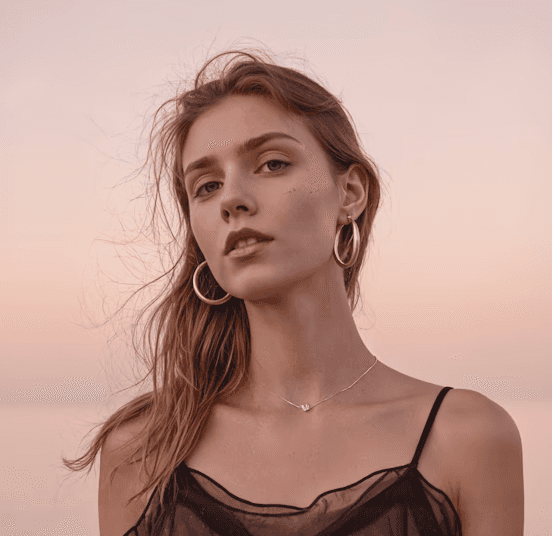 Woman meditating in forest sunlight beside a calm blue lake.