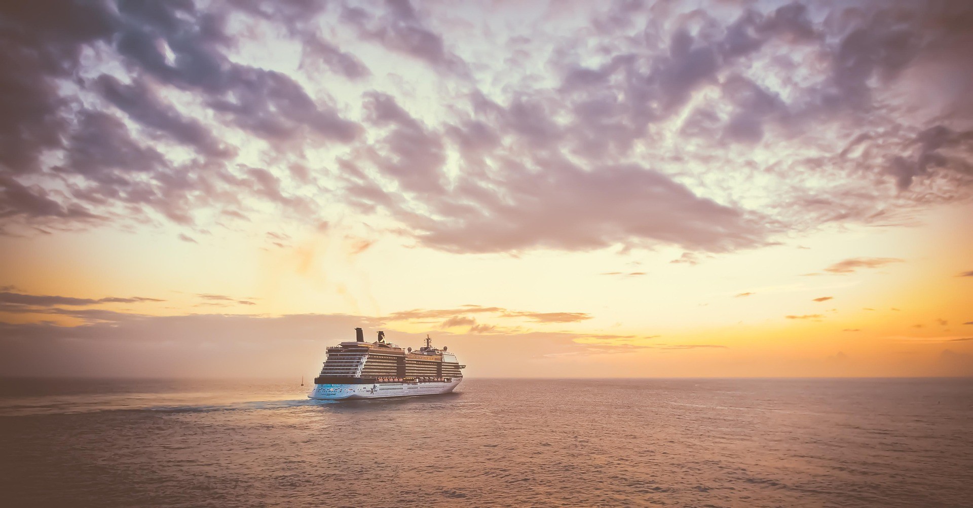 A cruise ship at sunset on the open sea.