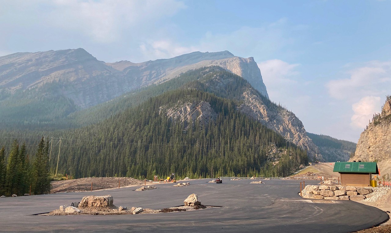 Expanded Grassi Lakes trailhead parking with washroom facility and native stone landscaping beneath rocky cliffs