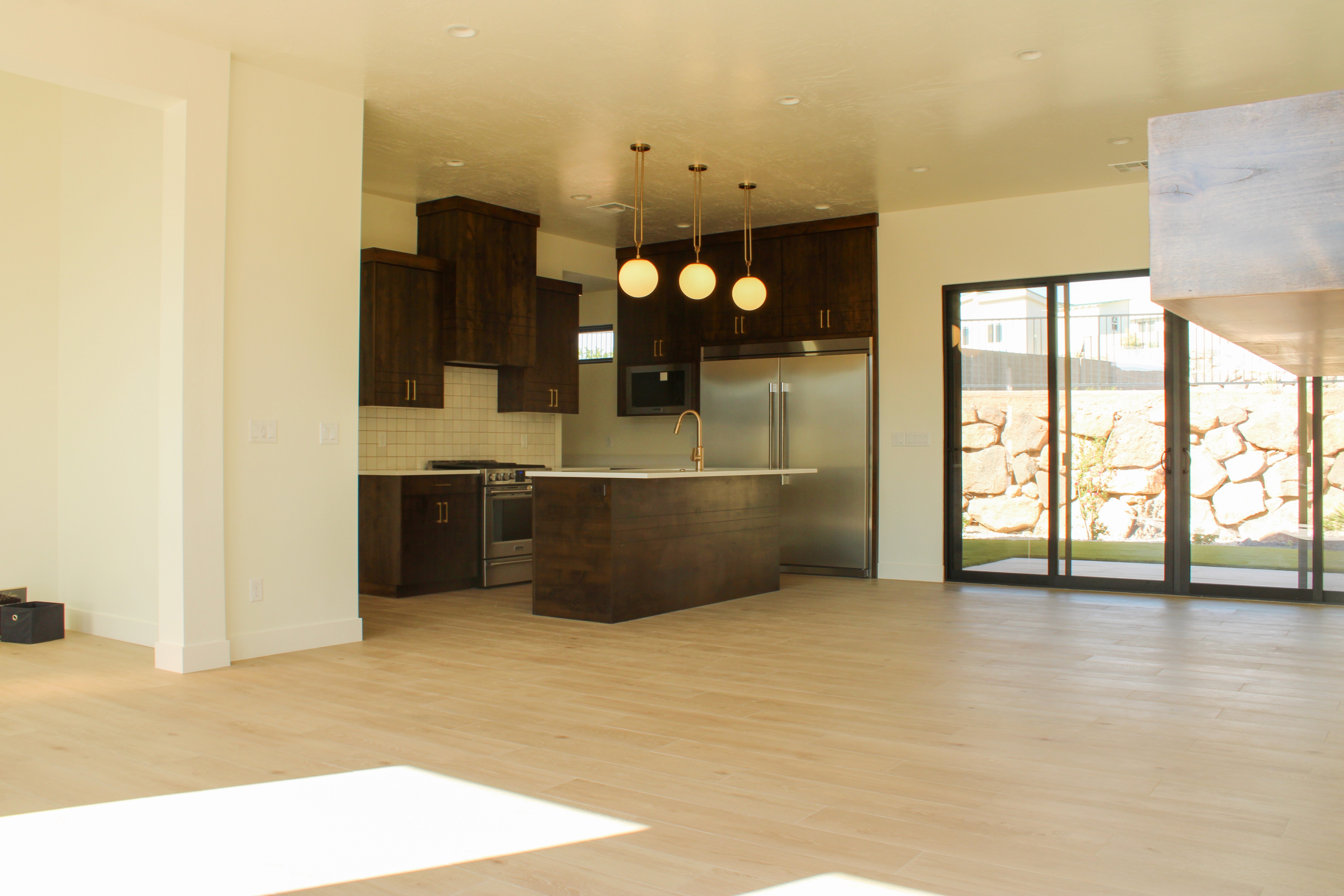 Kitchen with island and dark wood cabinets in The Overlook at Falcon Ridge, Hurricane, Utah, showing open layout living space.