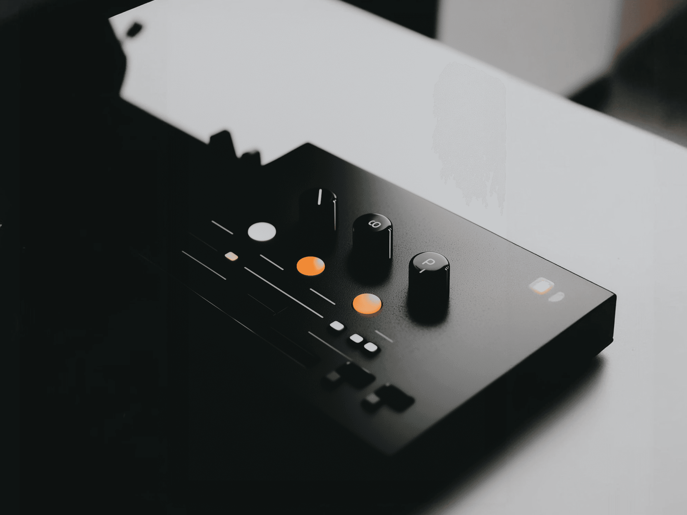 Close-up of a black audio controller with glowing orange knobs, sliders, and buttons, showcasing a sleek and modern design.
