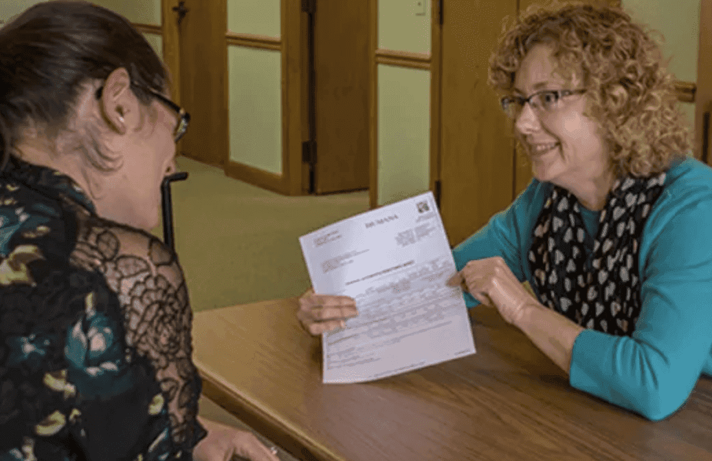 person writing on brown wooden table near white ceramic mug