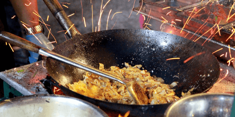 Char Kuey Teow dimasak dalam kuali panas menggunakan dapur arang.