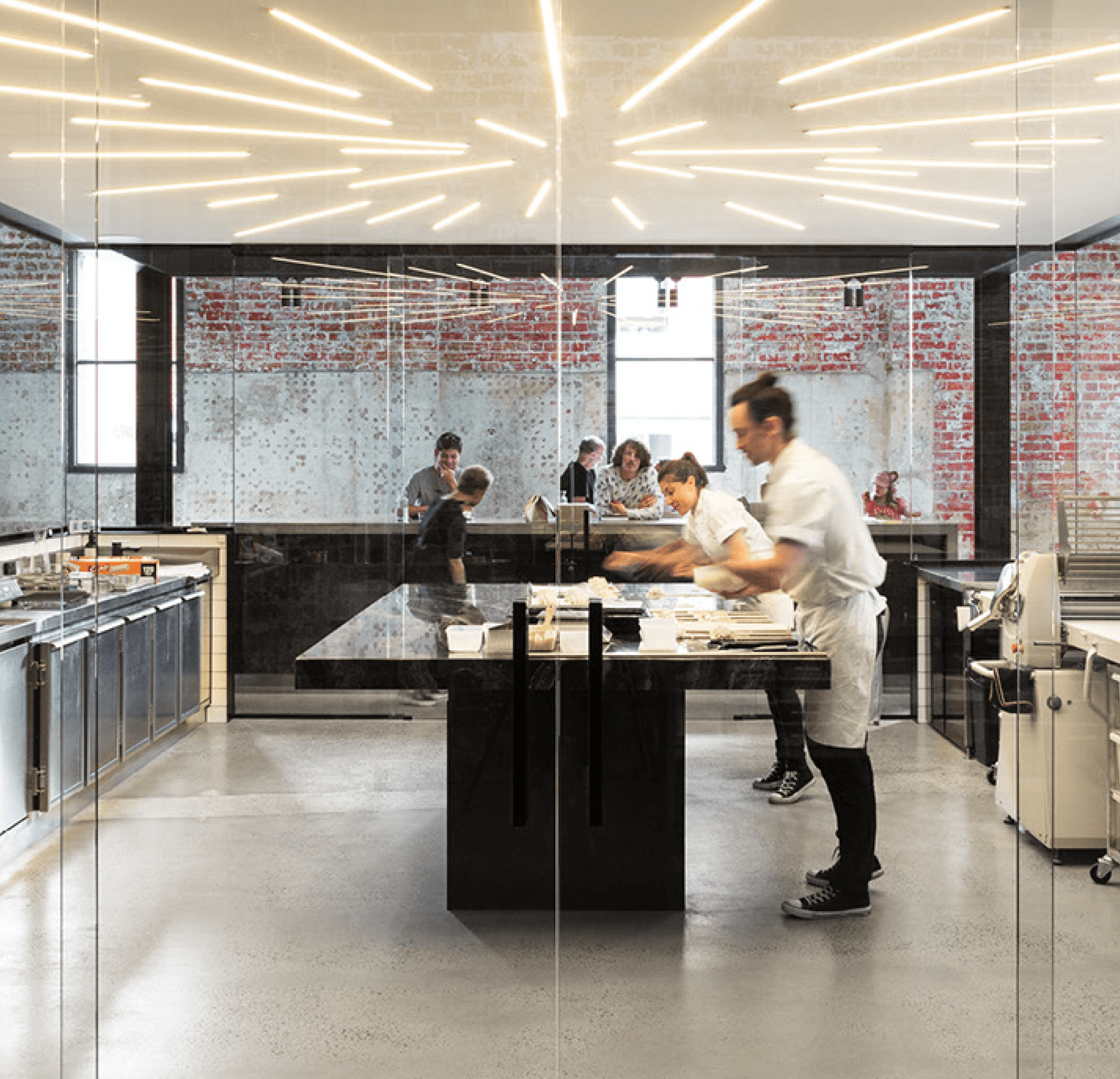 Bakers working at Lune, in a modern restaurant kitchen with exposed brick walls and designer lighting