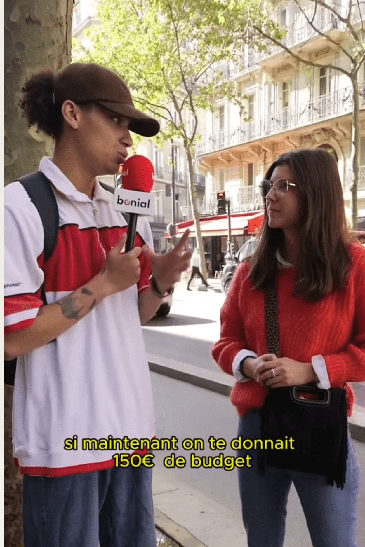 A young man in a white shirt and tie sits on the floor, surrounded by scattered papers. He looks down at a document, appearing focused and pensive.