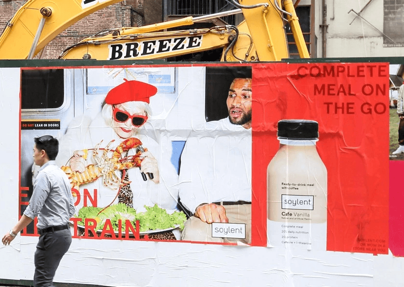 An outdoor ad for a Soylent campaign called Eat on the Train featuring a woman eating a whole lobster on the subway.