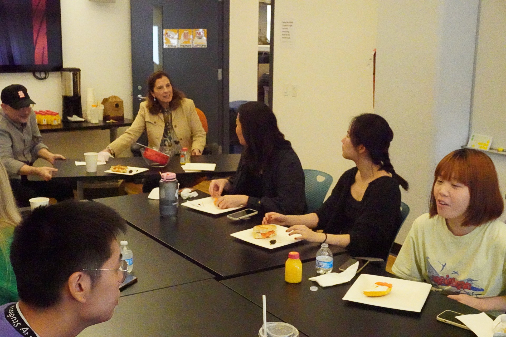 A photo of a group of people, talking while sitting at a conference table in an office room.
