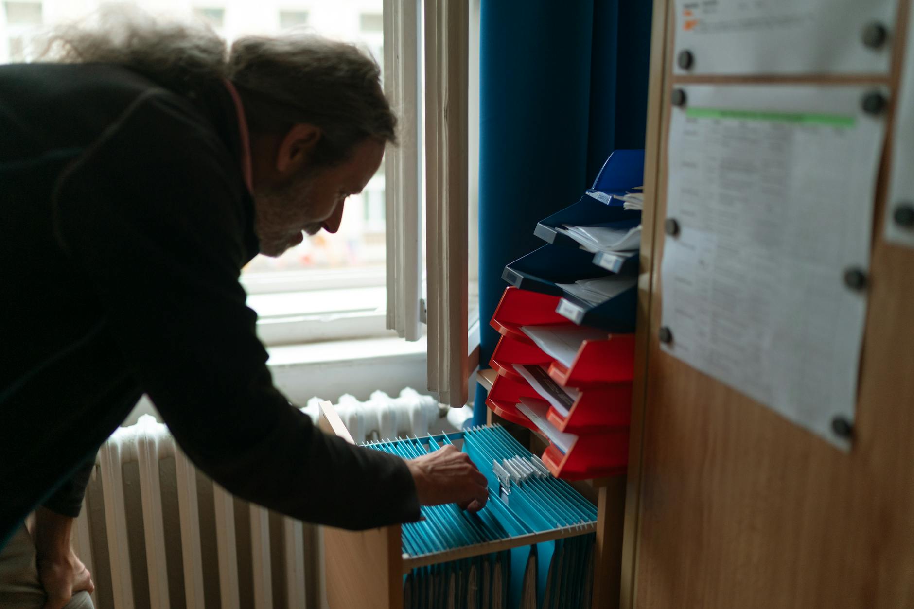 Color-coded hanging file folders in a plastic bin labeled for efficient classroom organization.