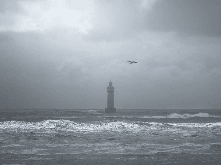 A lone lighthouse standing in the middle of a choppy, dark sea under a heavy gray sky, titled 'Finding Inspiration in the Storm'.