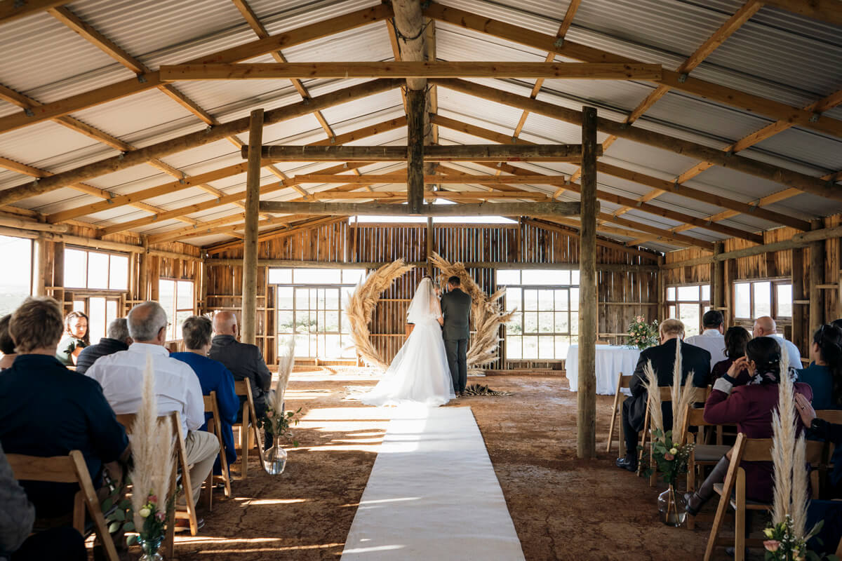 Wide shot of bride and groom standing at ceremony altar at Lombardini