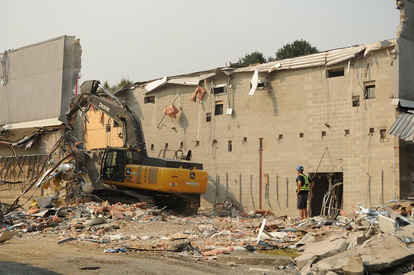 Universal Construction excavator knocking down the old theatre's block wall at the Cottonwood Apartments site, Chilliwack