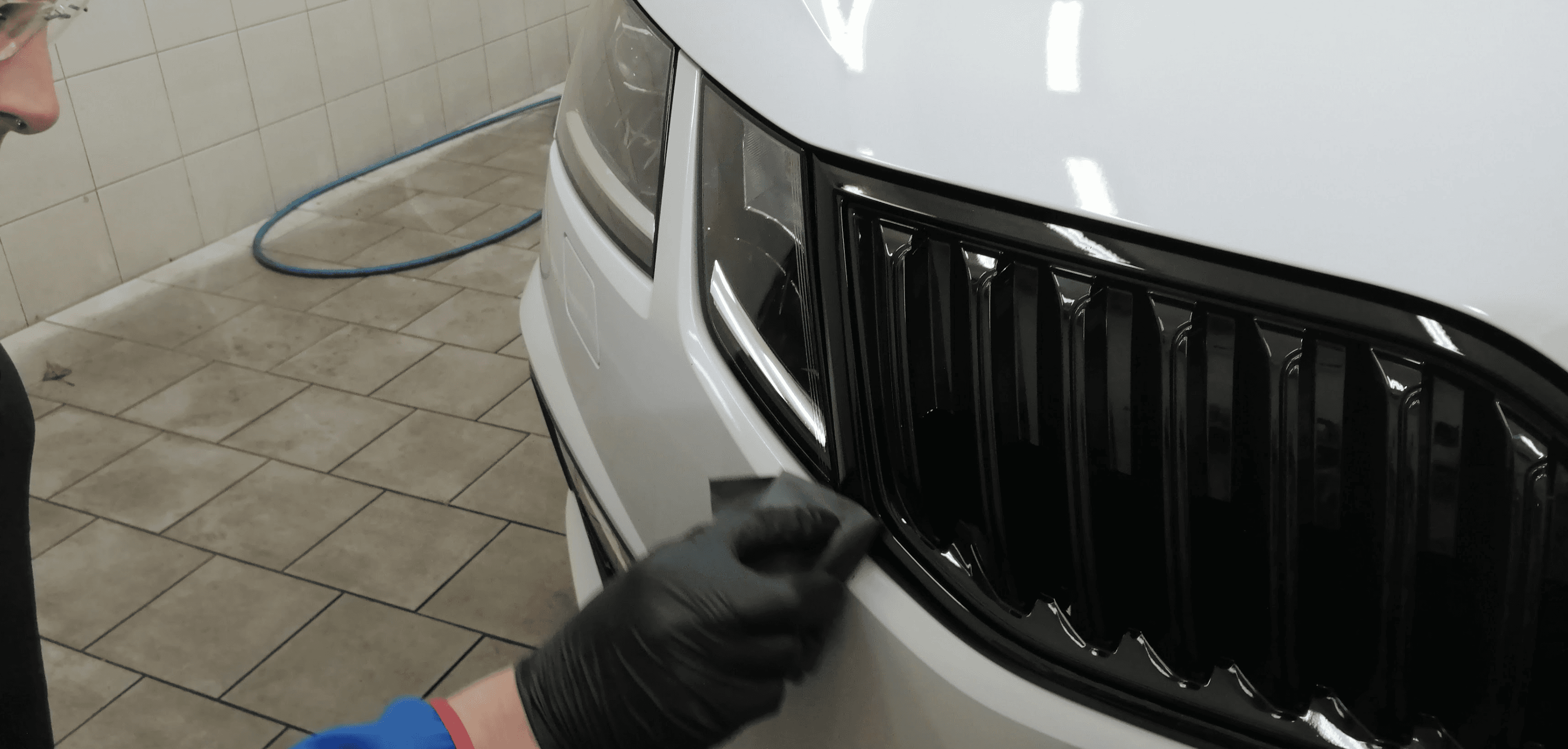 Detailní čištění mřížky chladiče a loga Škoda pomocí detailingových štětců.