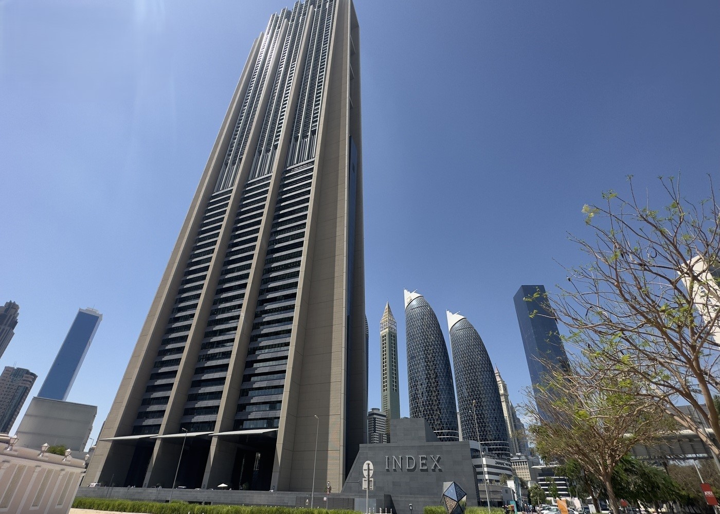 Real estate agent showcasing the iconic Index Tower within the DIFC skyline under a clear blue sky.