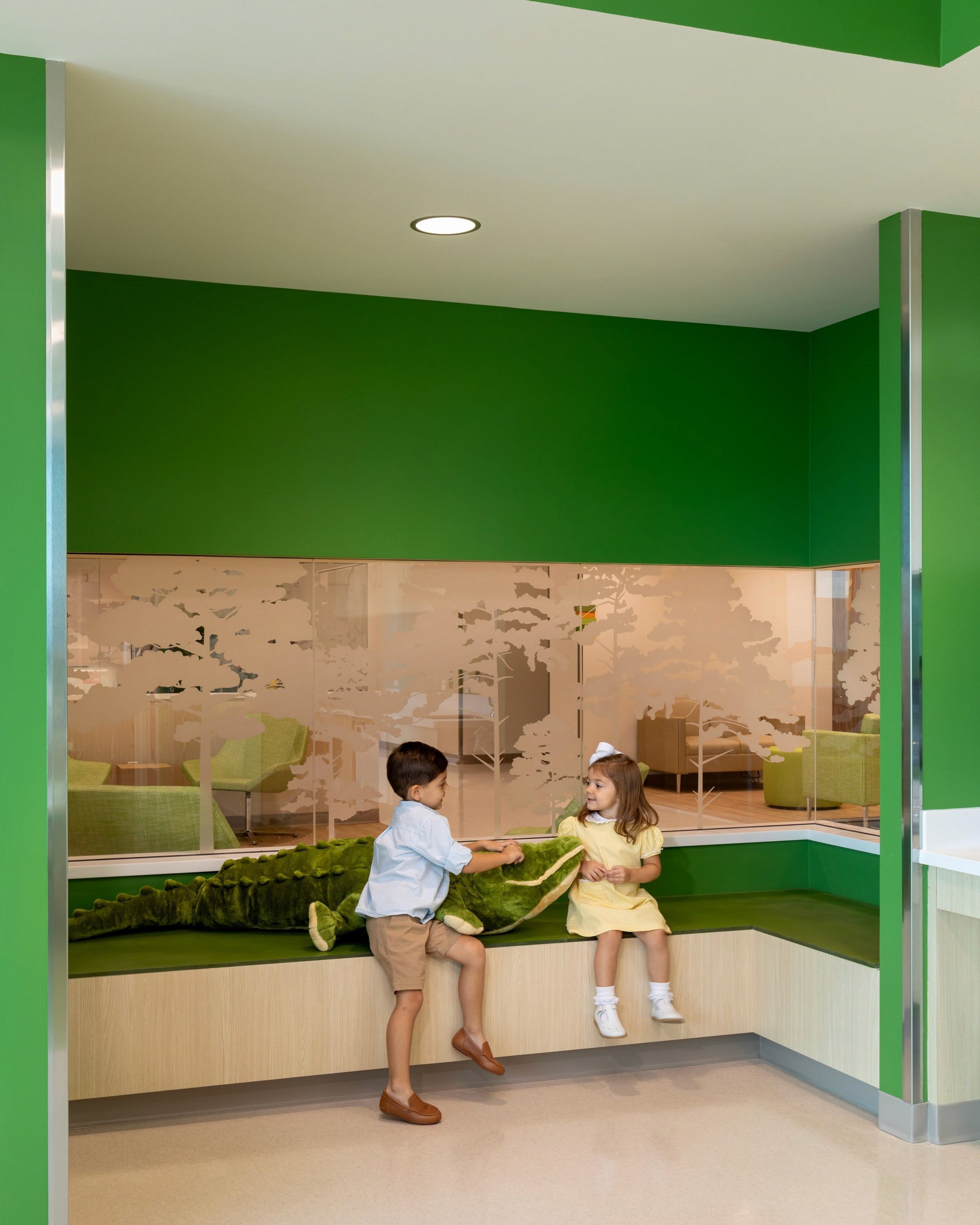 Children with stuffed alligator in green room.