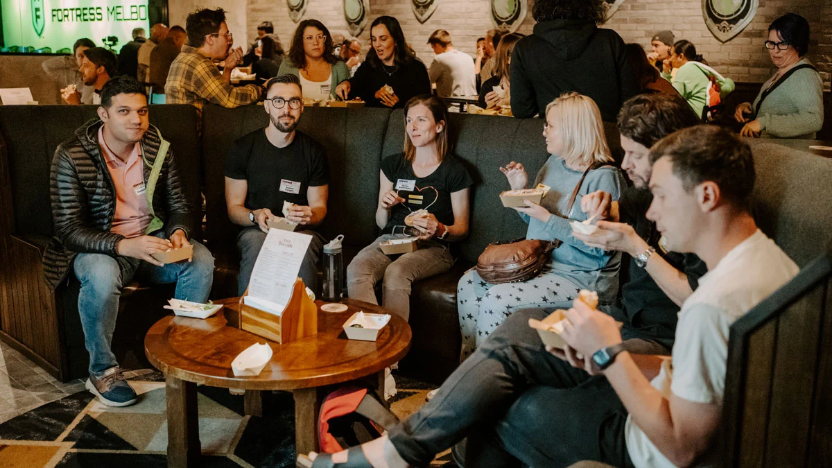 Group of various people sitting in a booth in the Tavern eating food