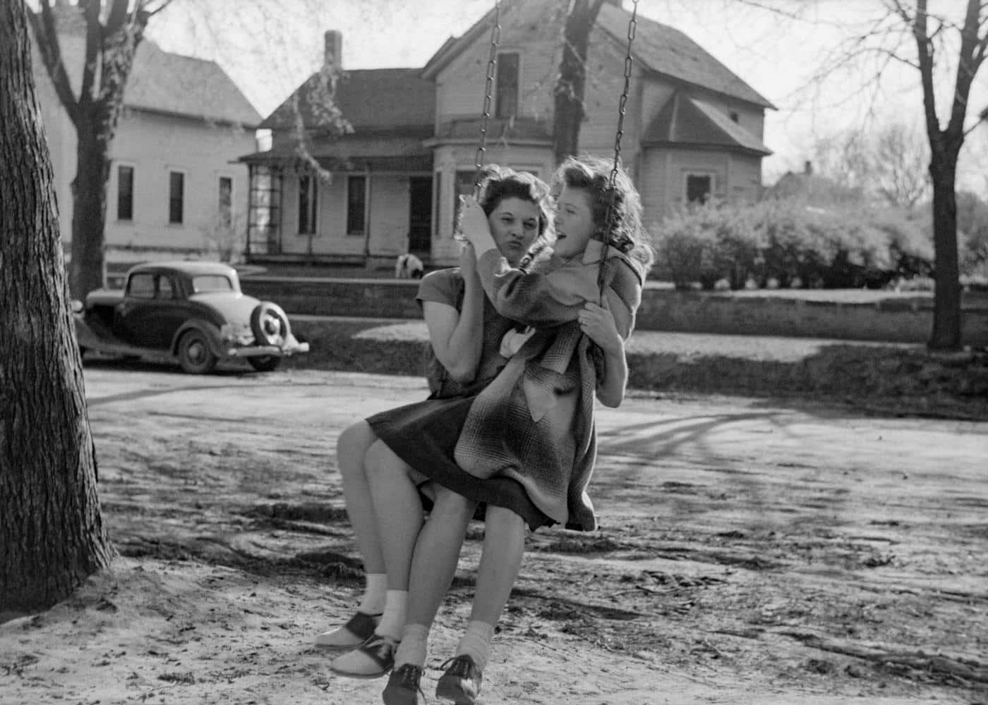 B&W image of two women on a swing attached to a tree