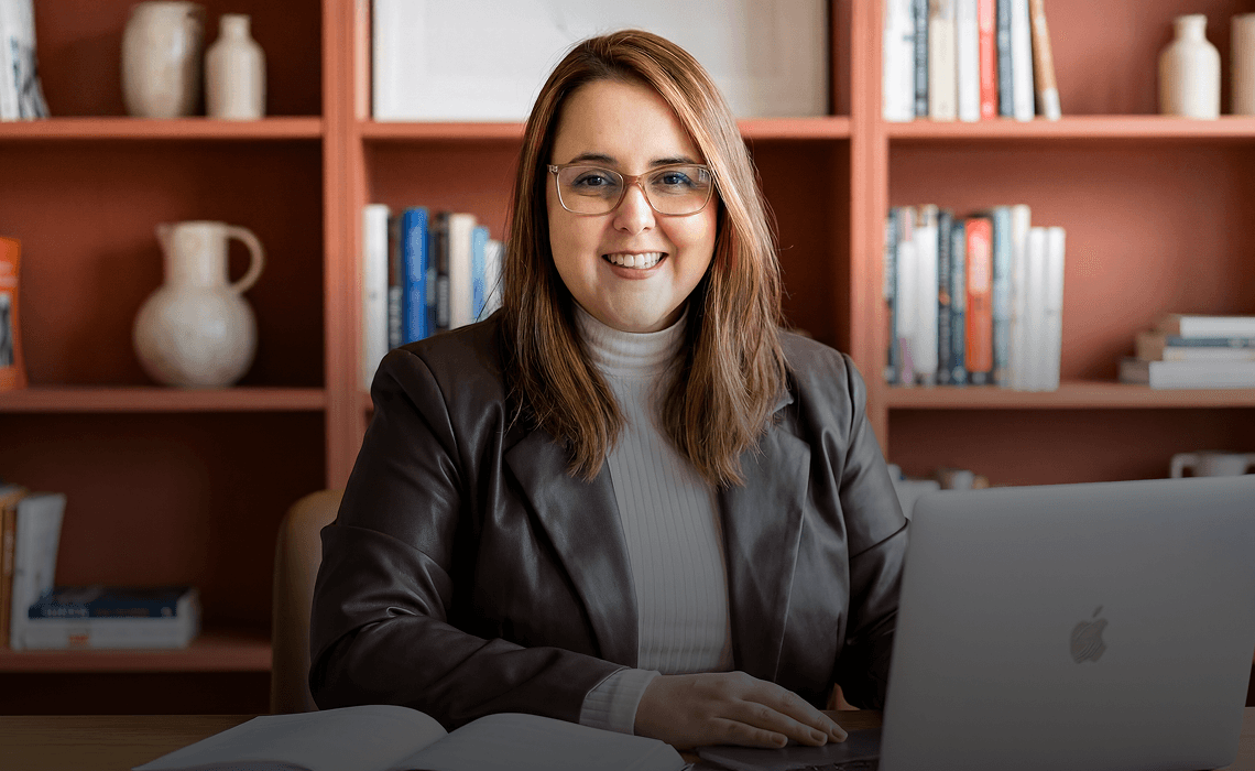 Nathalia Bittencourt, business consultant, smiling at her desk