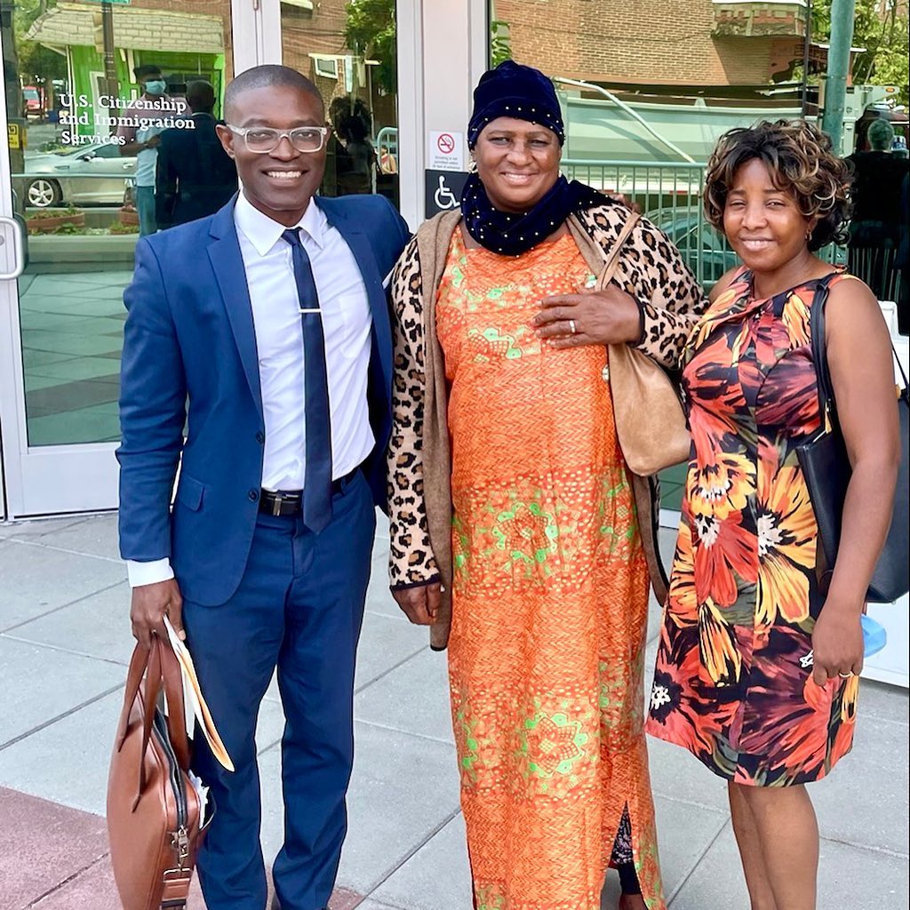 Kodwo Ewusi, CEO and Lead Immigration Attorney at Fibi Law Firm, smiling with satisfied clients at a USCIS office.