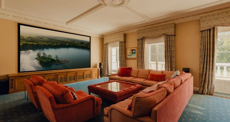 a living room with three sofas and a large painting of a lake
