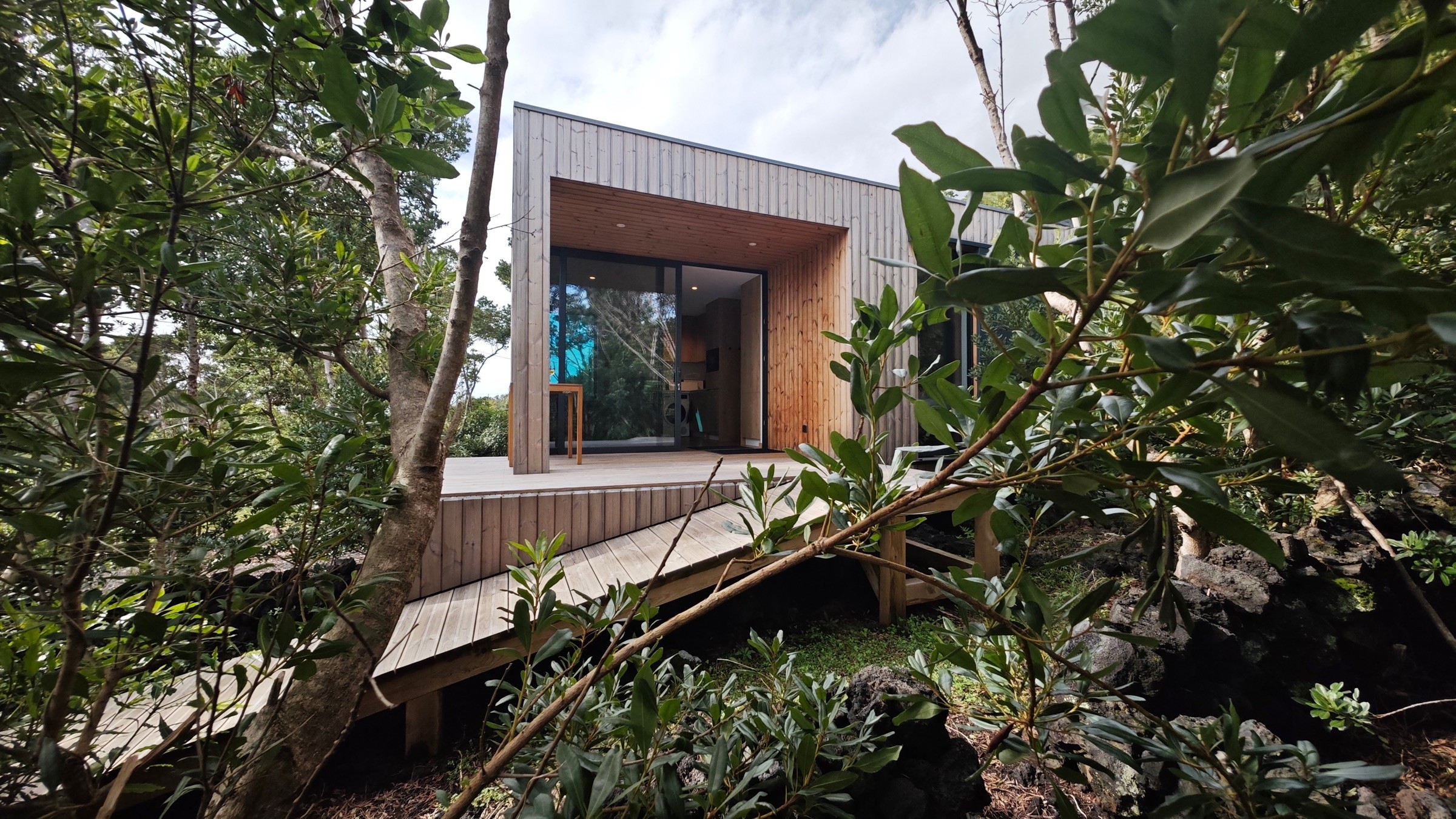 East view of the lodge showing the access ramp, deck, and sliding glass doors to the living room