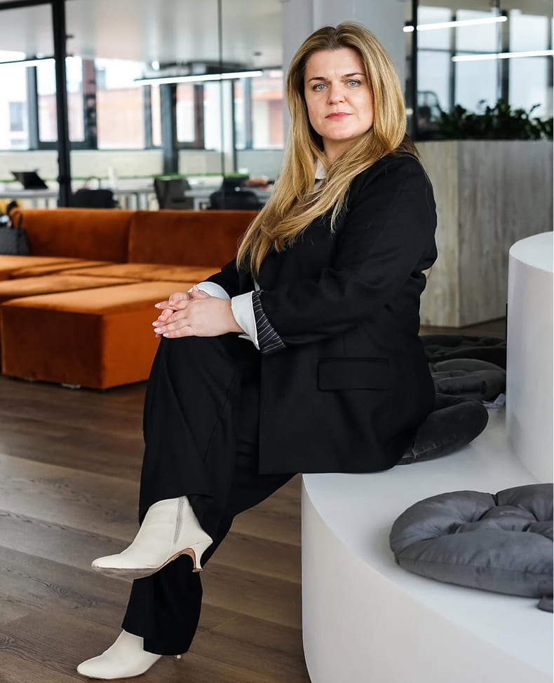 Black-and-white portrait of a man with an afro in motion, wearing a hoop earring and chain necklace, against a light gray background.