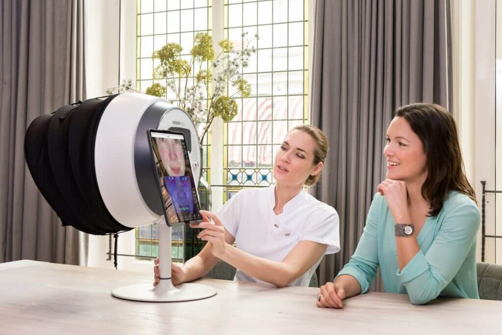 Specjalistka przeprowadzająca diagnostykę skóry za pomocą urządzenia do analizy.