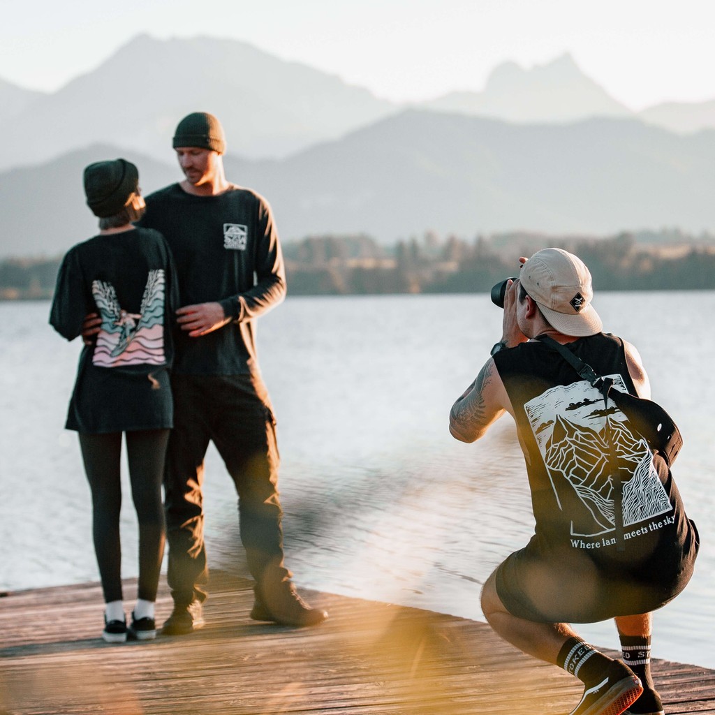 Kane photographs a couple standing on a pier.