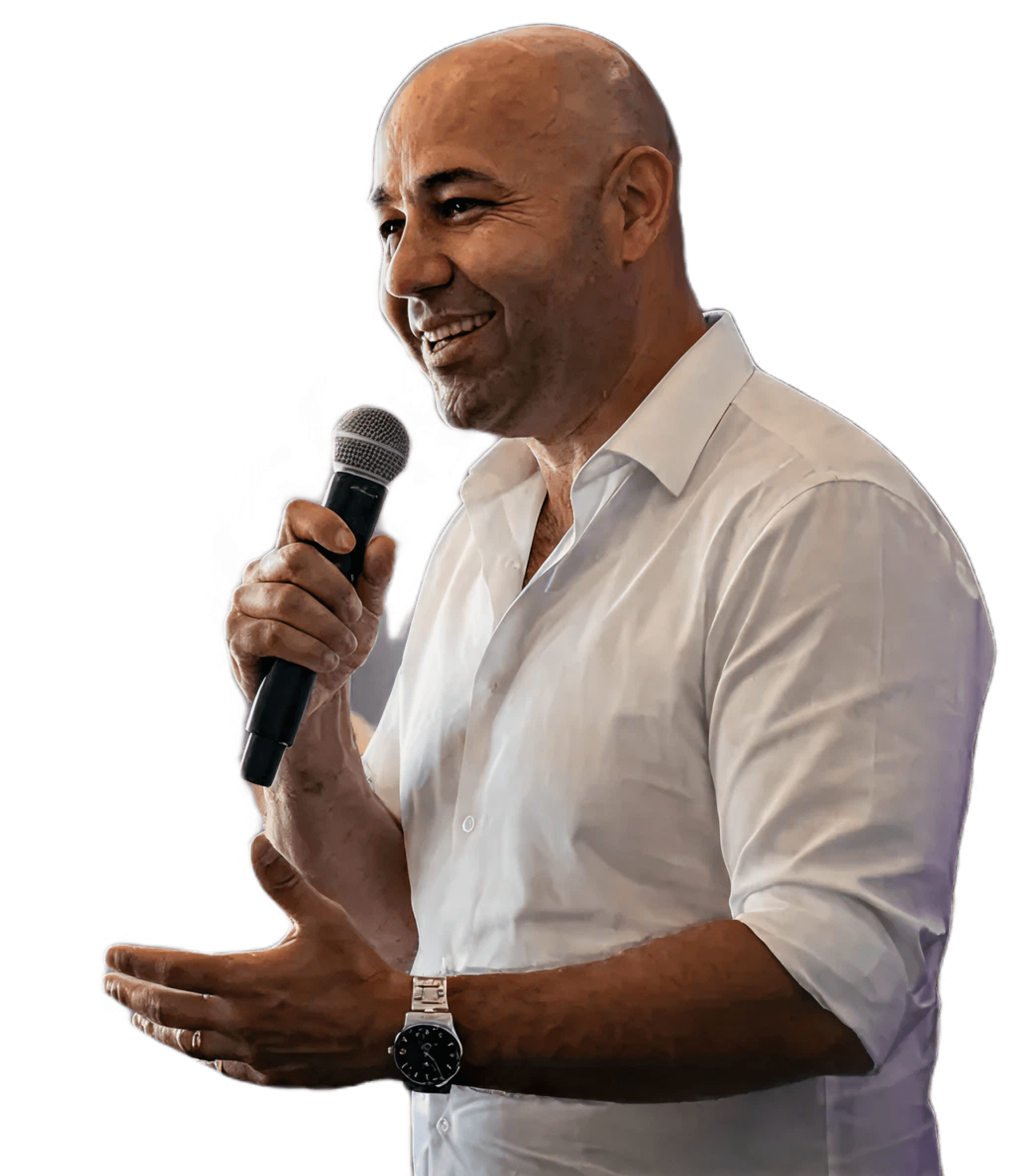 A person with a microphone smiles while speaking, wearing a light-colored shirt, against a neutral background.