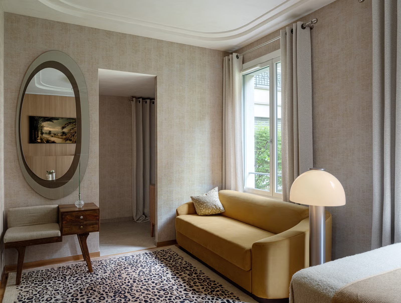 Décoration de salon avec papier peint texturé, miroir ovale rétro et luminaire blanc design pour un studio de standing.