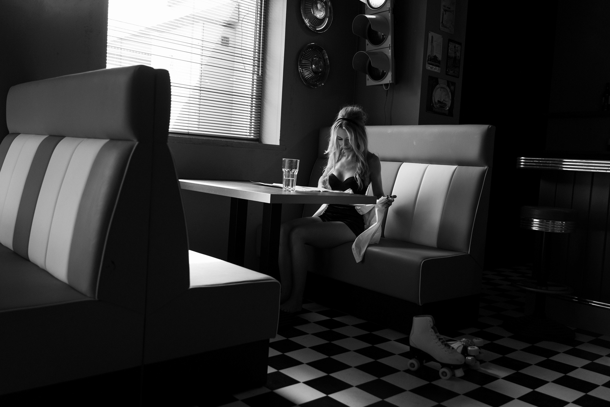 Agnieszka Czyzkowska fine art photography Warsaw woman sitting in diner booth holding shirt roller skate on floor black and white - still project 
