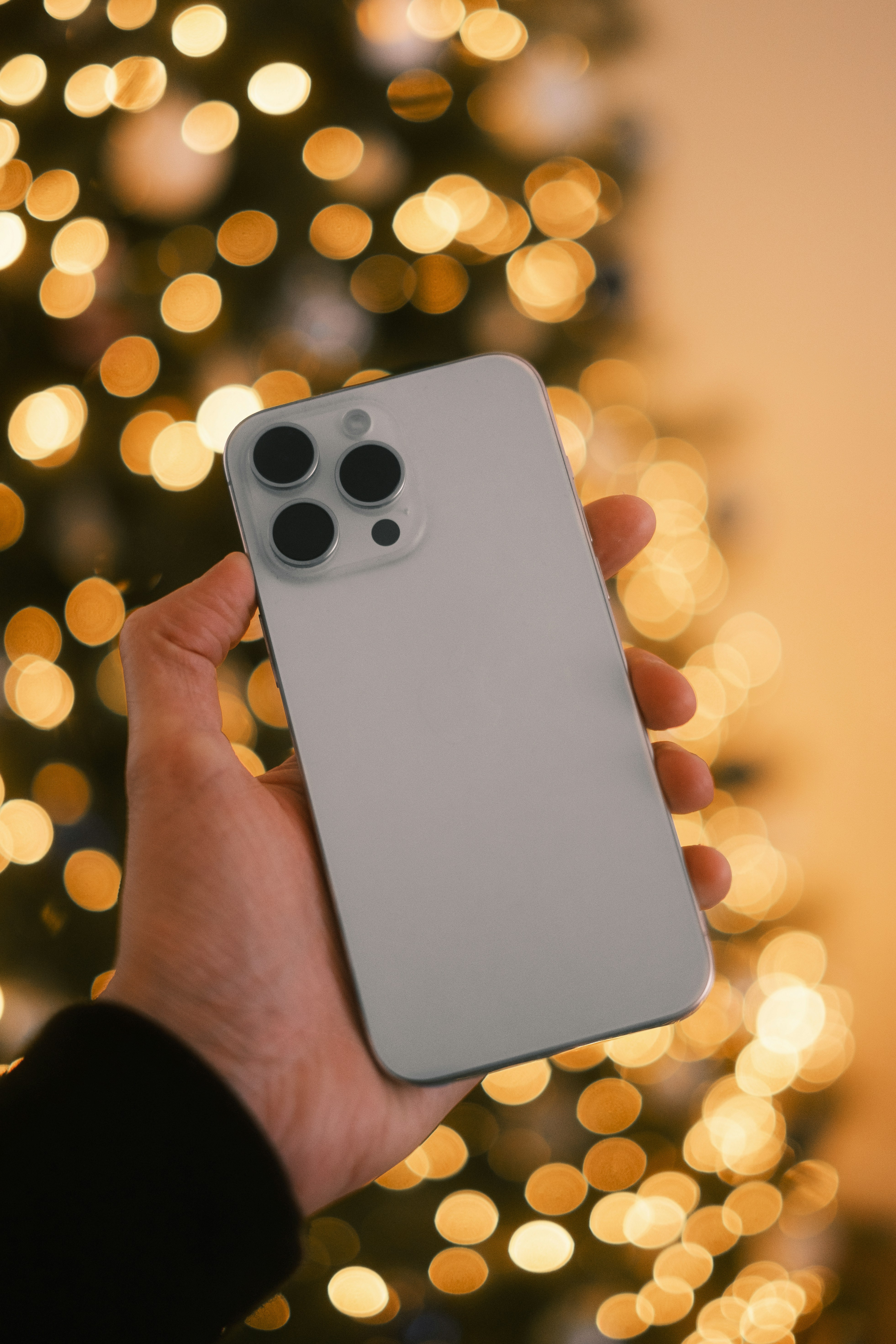 A person holding a cell phone in front of a christmas tree