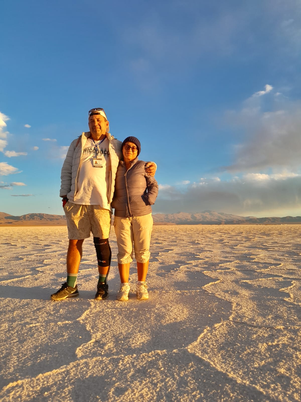 Mujer sentada sobre un tronco frente a una cascada doble en un bosque frondoso de Argentina.