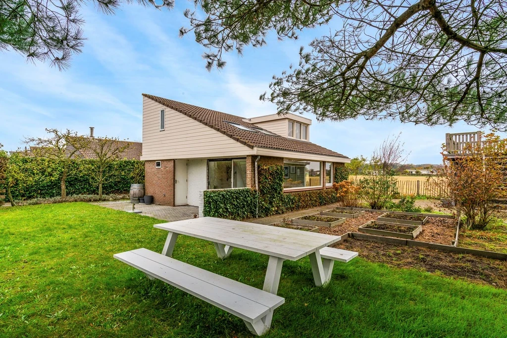 Garden of a detached house with a picnic table and open fields behind