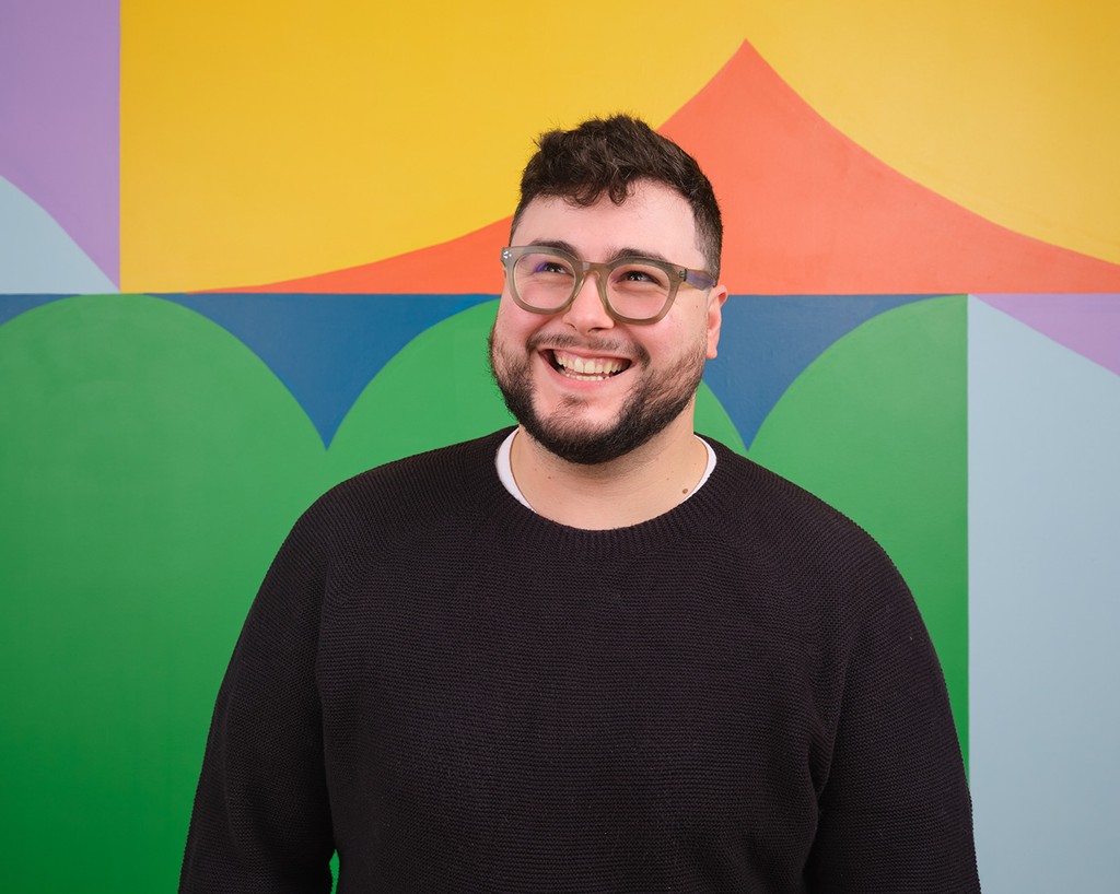 Portrait of Antoine Balouka-Chadwick standing in front of a colourful mural