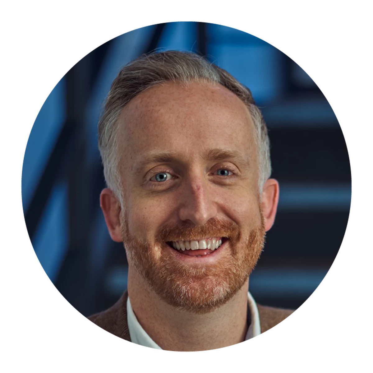 A circular portrait shows a person with short grey hair seated indoors. A modern staircase or architectural structure is visible in the background.