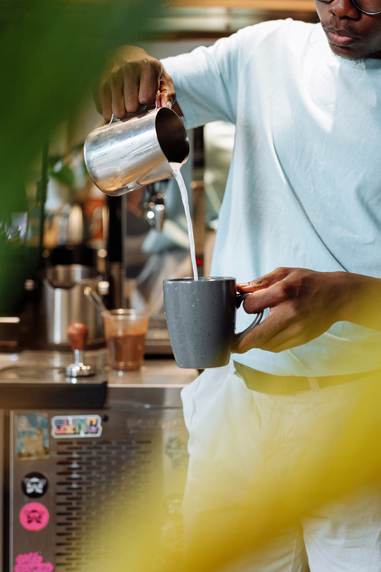 Barista pouring frothed milk into coffee cup